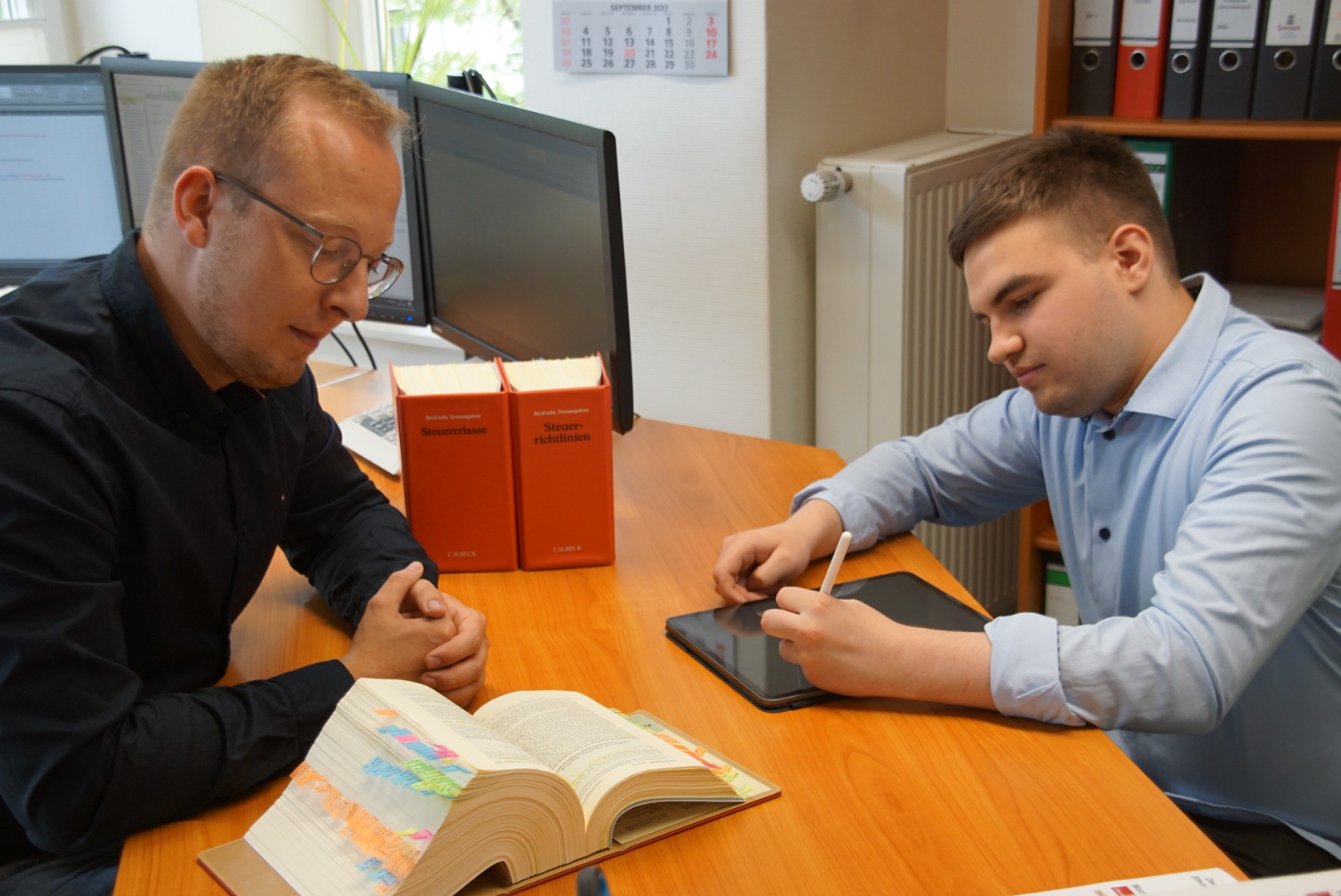 Zwei Mitarbeiter recherchieren im Gesetzbuch